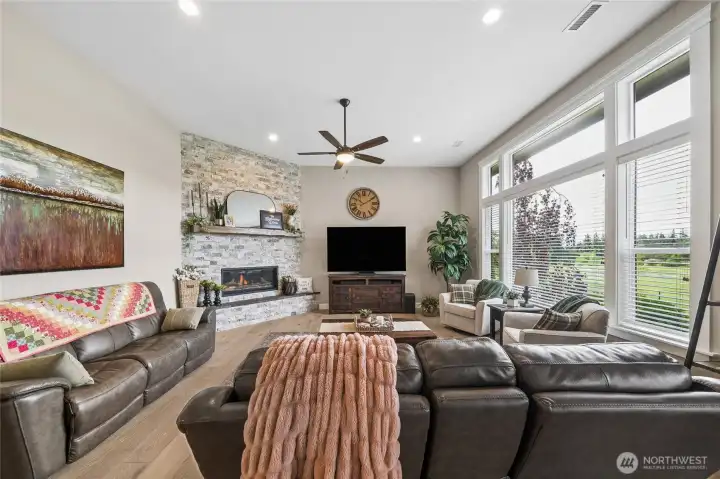 The bright and airy living room offers beautiful views of the sprawling rear property and a stunning stone-wrapped gas fireplace, creating a warm and inviting atmosphere filled with comfort and natural beauty. The bright and airy living room offers beautiful views of the sprawling rear property and a stunning stone-wrapped gas fireplace, creating a warm and inviting atmosphere filled with comfort and natural beauty.