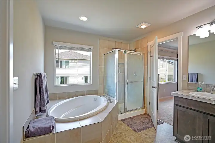Primary ensuite soaking tub with glass enclosed/tile shower