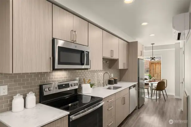 The pristine kitchen features premium stainless steel appliances, custom cabinetry & tilework.