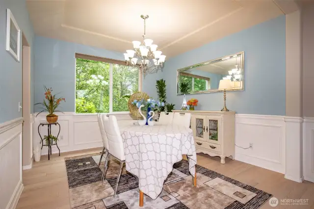 Dining Room with Wainscotting & Coffered Ceiling open to Living / Kitchen.