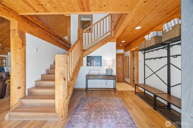 Welcoming foyer illuminated by warm wood tones and a graceful staircase, setting the tone for the lodge-style sophistication carried throughout the home.
