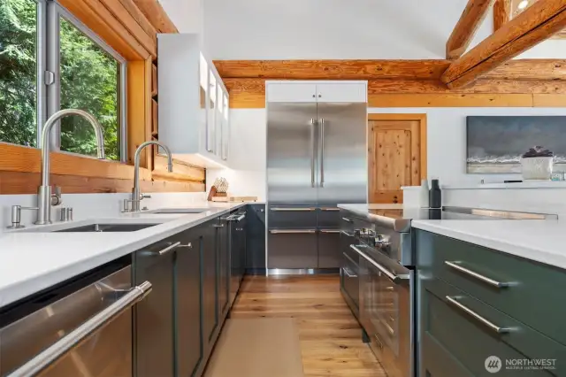 Thoughtfully designed for both form and function, the kitchen features dual sinks, top-tier appliances, and custom cabinetry—all bathed in natural light with sparkling ocean vistas beyond.