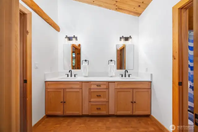 Stylish and spacious, this bathroom offers double sinks, premium fixtures, and timeless design with wood cabinetry and vaulted cedar-clad ceilings.
