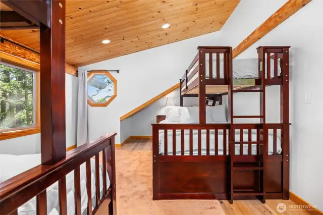 Vaulted ceilings and oversized windows flood this flexible upper-level bedroom with natural light. The space is ideal for guests or family, with ample room to play or relax.