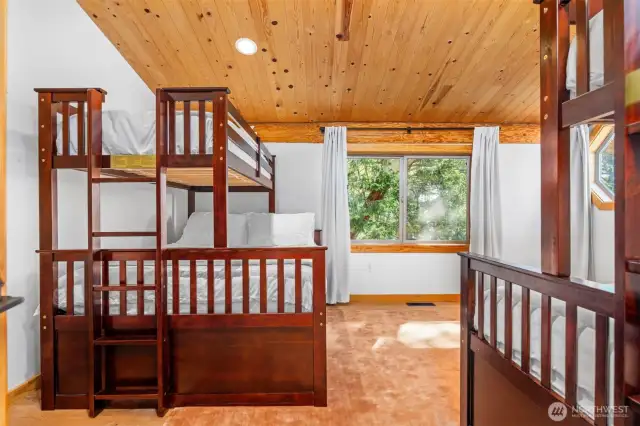 A second view of the bunk room highlights warm wood ceilings and a generous layout — perfect for large gatherings or multi-generational stays in this island retreat.