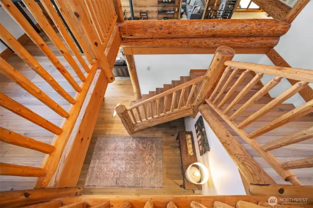 Bird’s-eye view of the custom log staircase showcasing its hand-crafted construction and rich wood grains that connect all levels of the home with rustic elegance.