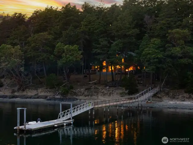 Glide in from the water and arrive directly at your property via the 40’ shared dock. This intimate view emphasizes the property's rare waterfront access and the welcoming glow of the home beyond.