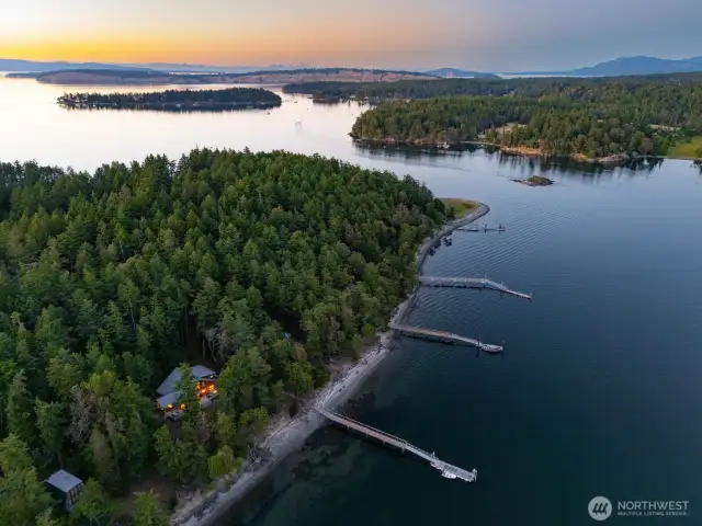 This overhead shot reveals the home's secluded location tucked within a lush evergreen forest, with direct access to the shoreline and a private dock—just minutes by boat from Roche Harbor.