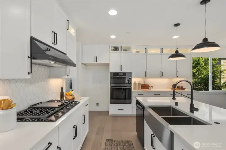 Kitchen Detail: Designer kitchen with sleek cabinetry, gas cooktop, double ovens, and custom tile backsplash, blending beauty with everyday efficiency. Thoughtful design provides plenty of prep and storage space.  Staged photos are of the model home of the same floorplan within the Foxmoore community and are for visualization purposes only. Colors, finishes, and layout can and will vary.