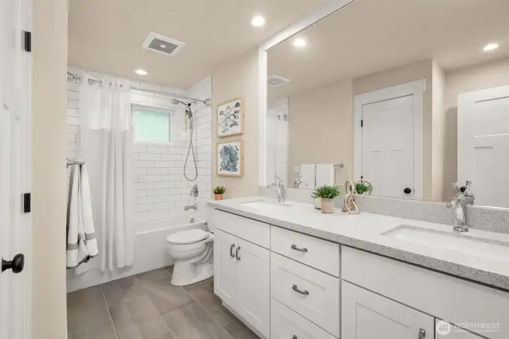 Updated full bath with dual sinks, quartz counters, and subway tile surround. Updated full bath with dual sinks, quartz counters, and subway tile surround.