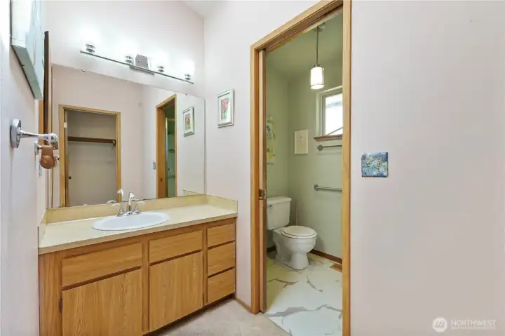 Primary bathroom has been semi-updated, with pocket door connecting toilet and large walk-in shower