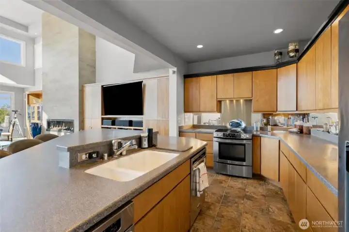 Ample prep space, cherry wood finishes and open sightlines.  Stainless steel appliances include French door fridge, trash compactor, microwave, dishwasher and glass-top stove.  Built-in cabinetry for a very large TV along the wall.