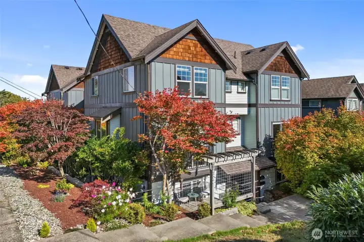 Charming craftsman townhouse with lush landscaping and inviting patio