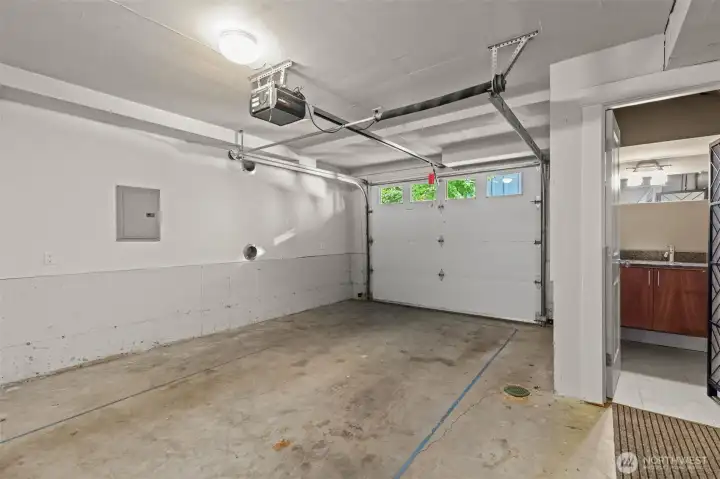 Spacious attached garage with extra storage and access to half-bath