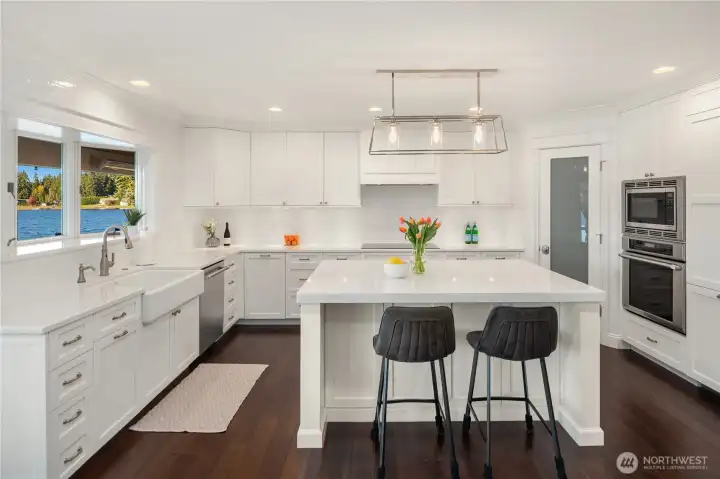 The bright, open-concept kitchen is appointed with professional-grade Thermador appliances, a farmhouse sink, and exquisite custom cabinetry.