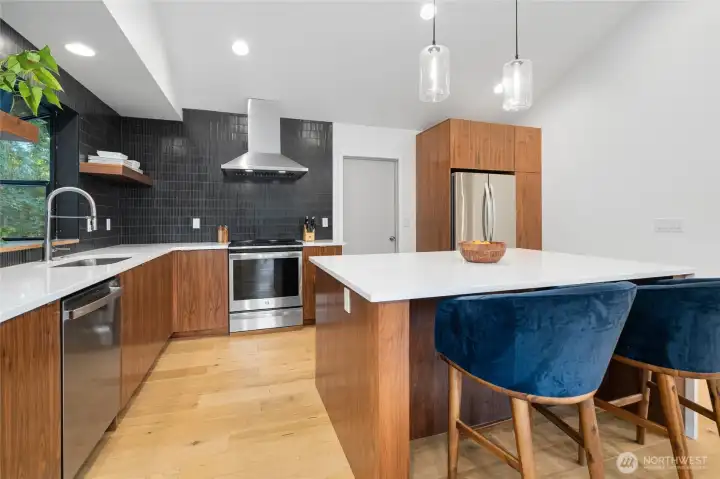 Gorgeous island kitchen with custom walnut cabinets, quartz, stainless appliances and glass & gold fixtures