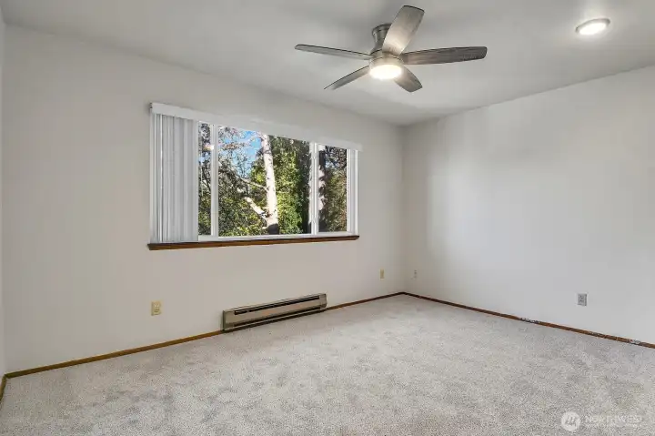 Second bedroom with a large picture window and ceiling fan to circulate the air.