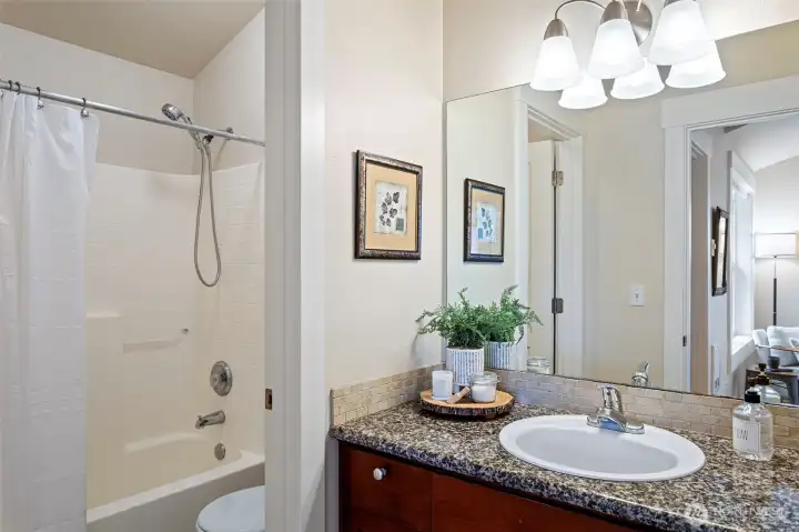 Full bathroom off the primary bedroom with a granite counter, tiled backsplash, full mirror, new shower head and full bath.