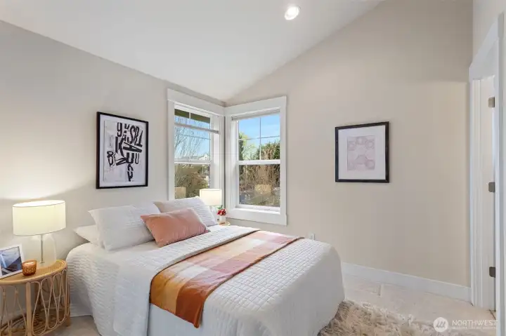 A second bedroom on the upper level is filled with natural light from corner windows—ideal as a guest room or home office.
