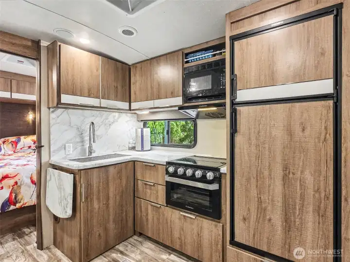 Full kitchen with modern cabinetry, stove, microwave, and refrigerator
