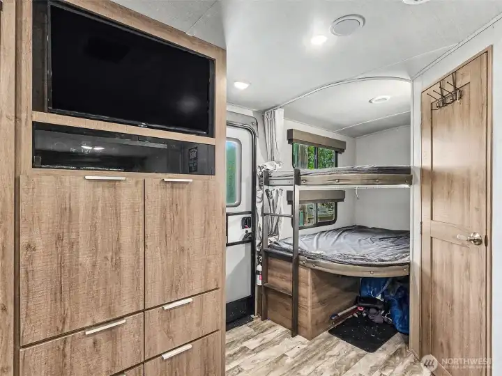 Built-in bunk beds with storage and mounted TV—efficient sleeping space for guests