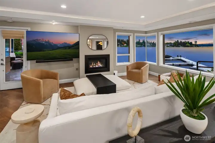 The living room is anchored by a welcoming sense of warmth — rich hardwood floors, a gas fireplace glowing at the heart of the space — but it's the wall of west-facing windows and their unobstructed view of Yarrow Bay that truly command the room. Sophisticated, serene, and utterly unforgettable