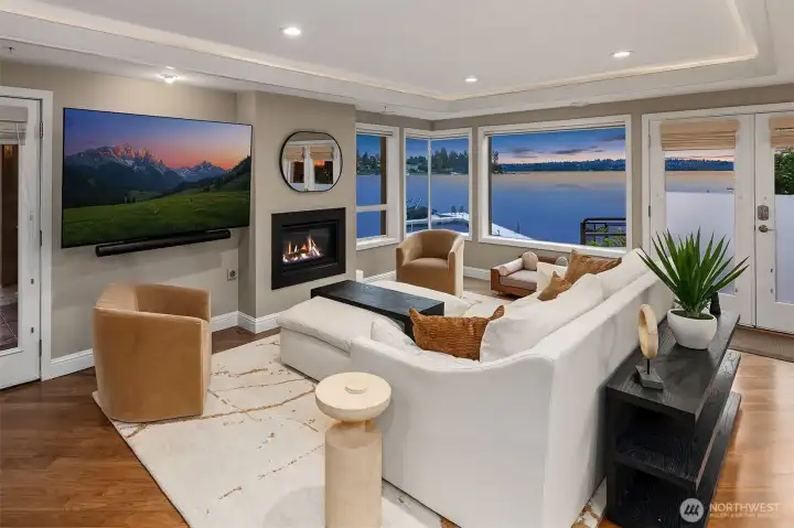 As dusk settles over Yarrow Bay, the living room transforms — firelight glowing against the last blue light of evening, the lake filling every window in the room's corner.  The soffited, backlit ceiling frames the room and creates a soft, sweet ambiance.