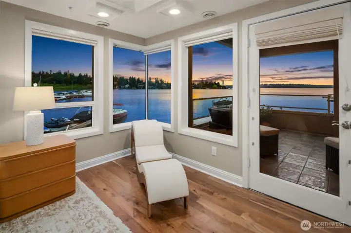 In the primary bedroom, corner windows wrap the sitting area in an unobstructed panorama of Lake Washington  while French doors lead directly to the expansive covered deck — seamlessly connecting the sanctuary within to the water beyond.