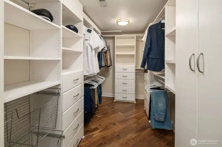 Storage this good deserves its own moment — a sprawling walk-in closet with fully custom built-ins, double hanging rods, pull-out hamper, and more drawer space than most homes offer in an entire bedroom. Beautifully finished with hardwood floors, it's the kind of closet that makes you want to own more things.