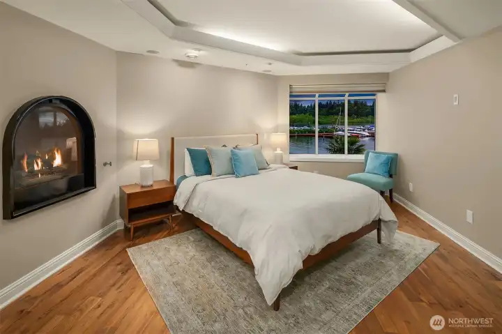 Guests may never want to leave. An arched gas fireplace glows against warm hardwood floors, while the window frames a serene view of the marina and lake beyond. With a tray ceiling, generous proportions, and thoughtful touches throughout, this secondary bedroom offers a stay that rivals any boutique hotel.