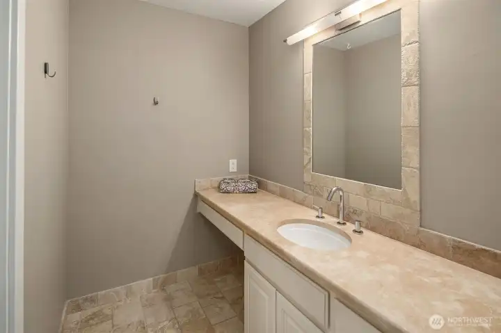 The en-suite bath extends beyond the shower to a clean, well-appointed vanity — stone countertop, undermount sink, and a generous mirror that keeps the space feeling bright and open. Every detail considered, nothing overlooked.