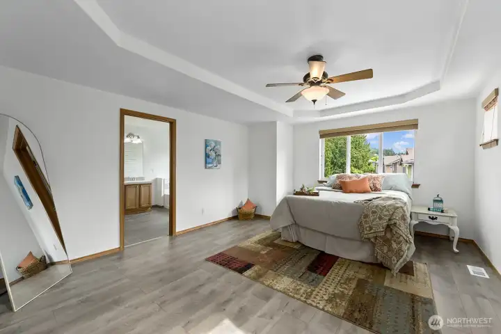 Primary suite features an elegant recessed ceiling with fan.