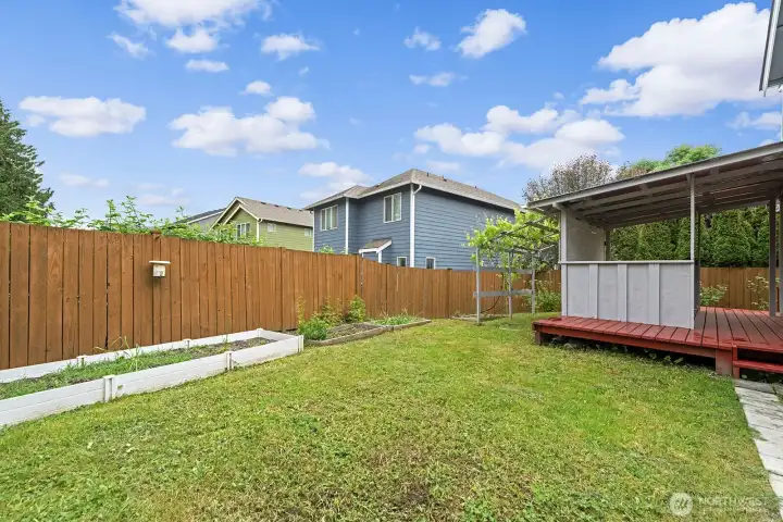 Back yard features covered deck, garden with fruit trees, shed, and greenhouse.