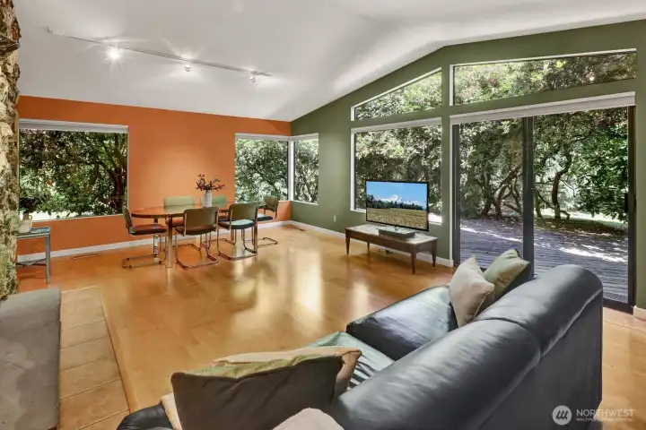 Living room with engineered wood floors with vaulted ceiling with windows allows the outside in. Sliding door to the wrap around covered deck. Living room with engineered wood floors with vaulted ceiling with windows allows the outside in. Sliding door to the wrap around covered deck.