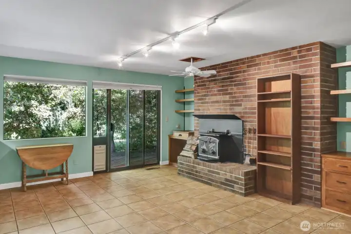 Wood burning fireplace with built in shelving and and cabinetry. Tile flooring with sliding door onto the back yard deck. Wood burning fireplace with built in shelving and and cabinetry. Tile flooring with sliding door onto the back yard deck.