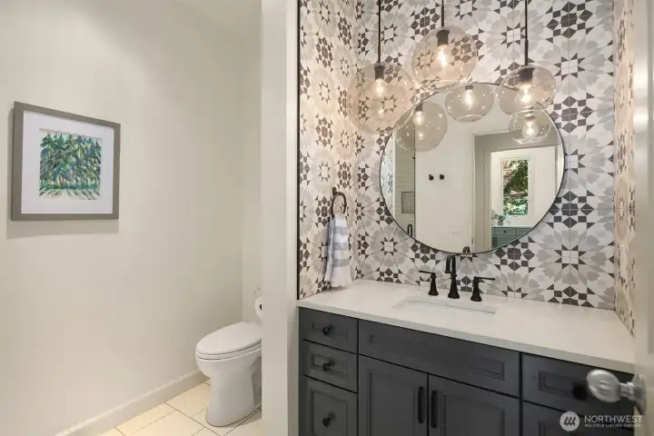 Main floor updated three-quarter bathroom with tiled, walk-in shower, quartz countertop, new  fixtures, modern tile backsplash, pendant lighting & new flooring. All bathrooms updated in 2021.