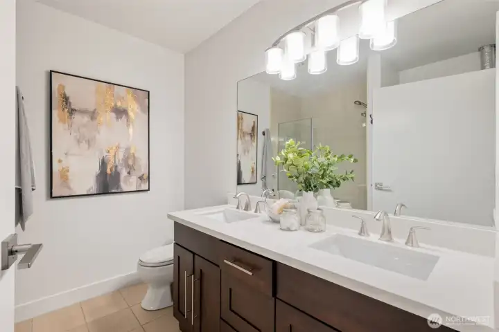The modern bath boasts a dual vanity, newly updated tiled walk-in shower and your convenient in-unit washer and dryer.