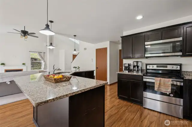 This kitchen is where function meets flair. The electric cooktop and microwave vent combo keep things sleek, while dark brown cabinets add that rich, on-trend tone. Neutral granite counters tie it all together for a space that’s ready for anything from a weeknight dinner to a weekend brunch.