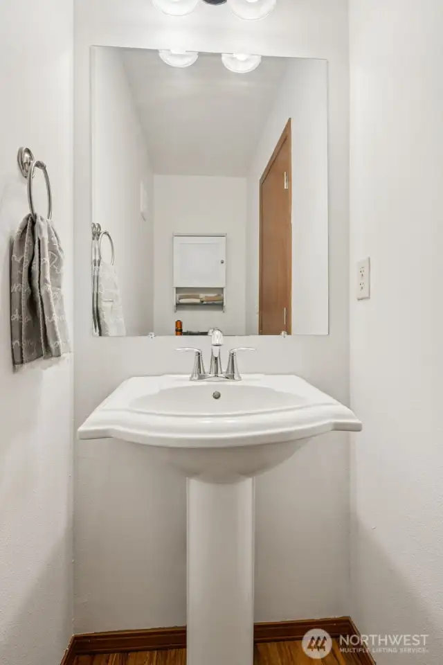 Tucked just off the entry, this powder room gets the job done with style. The pedestal sink keeps things classic, while wood laminate floors add a warm, modern touch. It’s the kind of space that’s ready for guests without needing a full refresh.