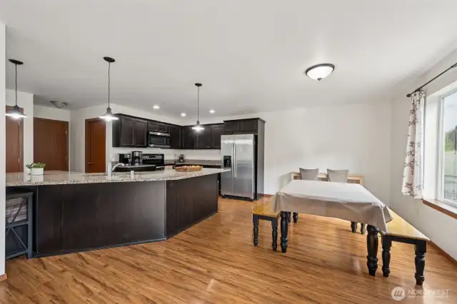 With granite counters for days and a peninsula that doubles as a breakfast bar and conversation hub, this kitchen layout just works. Dark Shaker cabinets give it a grounded, luxe look, and the dining area’s oversized window adds that breath of fresh air we all need.