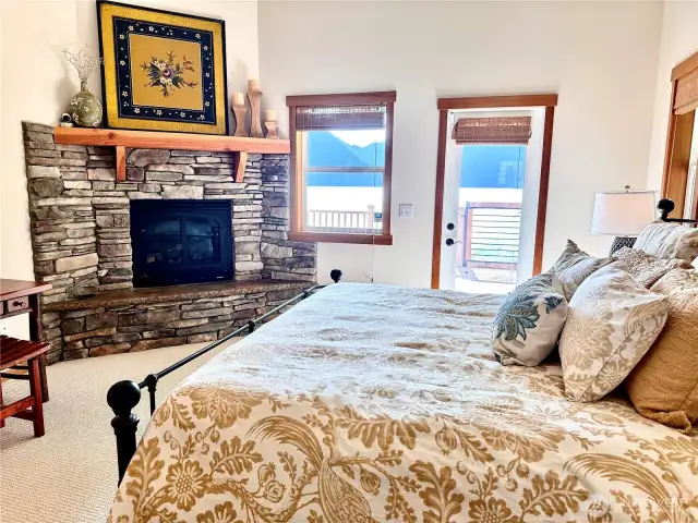 Luxurious primary bedroom w/ stone fireplace.