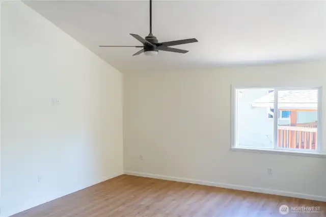 Living room features vaulted ceiling and fan.