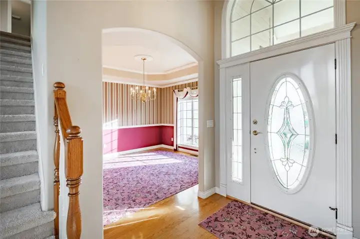 Entryway. Formal Dining room or Family Room in the background. Stairs going up to 3 Bedrooms a full bathroom and a bonus room. Primary bedroom is to the left when entering through the front door.