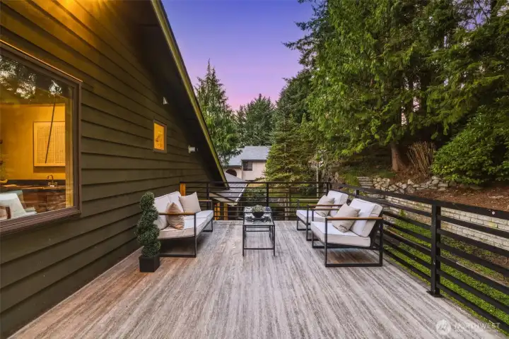 Expansive deck overlooking a private, tree-lined backyard with mature landscaping and patio—perfect for relaxing, entertaining, or gardening.