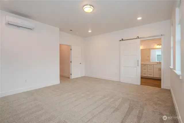 A charming barn door slides open to reveal the luxurious Primary Bathroom. The hallway to the left leads to the Utility Room, 2 additional Bedrooms, a full Bathroom and the stairway down to the main floor.