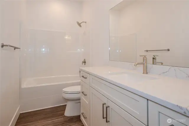 The Full Bathroom in the upstairs hallway boasts excellent storage space, quartz counters, a full bath/shower combo and luxury vinyl plank (LVP) flooring, blending modern style, durability and function.