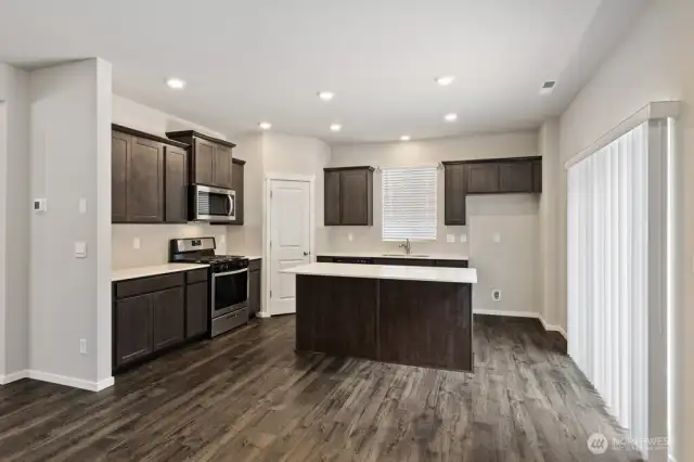 Kitchen offers slab counters, gas range, walk-in pantry and access to backyard via slider door. Colors, finishes, and options will vary.