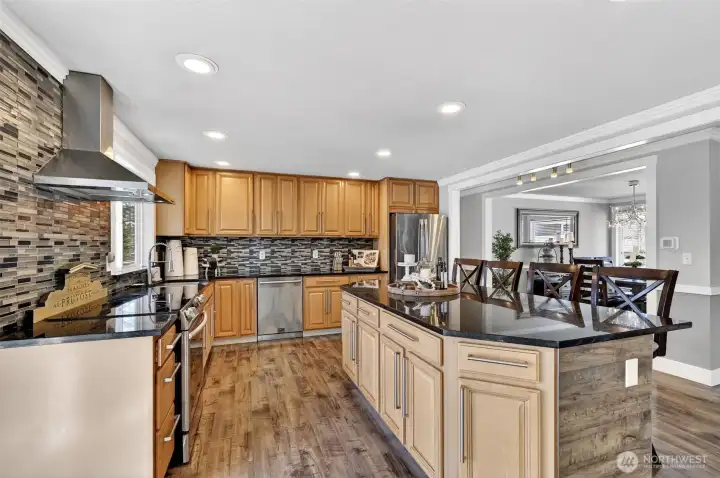Chef-style kitchen with expansive island, granite counters, mosaic backsplash, and abundant cabinetry for effortless hosting. Chef-style kitchen with expansive island, granite counters, mosaic backsplash, and abundant cabinetry for effortless hosting.