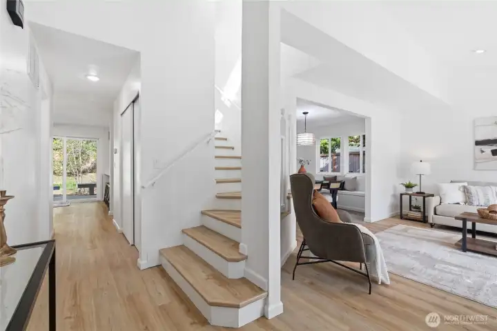 Bright, open entry with light wood-tone flooring, clean white staircase, and a seamless sightline to the backyard slider — the layout flows effortlessly from the moment you walk in.