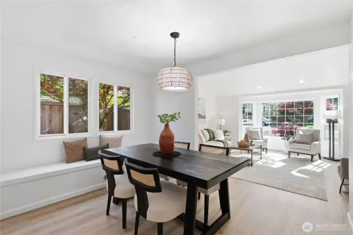 The dining area opens directly to the sunlit living room through a wide archway, creating an easy flow between spaces with garden-view windows and a statement pendant light.